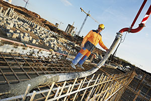 builder worker standing near trailer-mounted boom concrete pump on metal rods reinforcement of concrete casting formwork